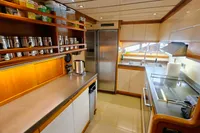 Luxurious yacht kitchen with modern appliances, wooden cabinetry, and ample storage, Custom Line 94, 2004.