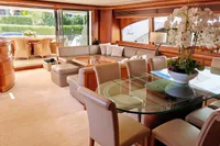 Luxurious yacht interior with elegant dining area, glass table, and plush seating, Custom Line 94, 2004.