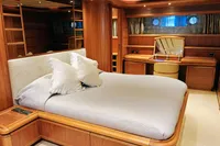 Luxurious yacht bedroom with wooden decor, Custom Line 94, 2004 model, featuring a cozy bed and vanity.