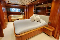 Luxurious yacht bedroom with wooden interior, Custom Line 94, 2004 model, featuring a cozy bed and sofa.