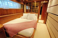 Luxurious yacht bedroom with wooden interior, cozy bed, and soft lighting, Custom Line 94, 2004 model.