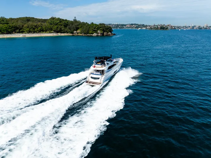 Just For Fun Yacht Photos Pics Luxurious 2011 Sunseeker Manhattan 73 yacht cruising on blue ocean near lush coastline.