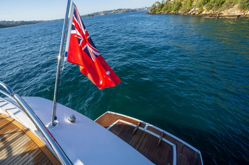 Just For Fun Yacht Photos Pics Sunseeker Manhattan 73 yacht, 2011 model, with a red flag, cruising on clear blue waters.
