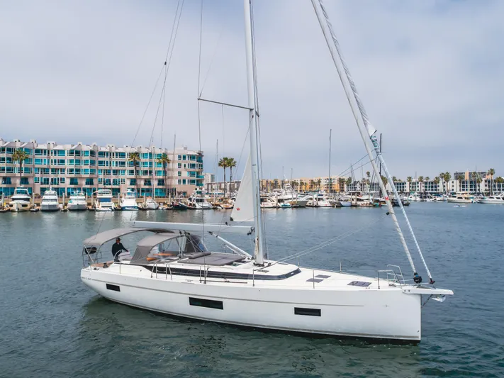 Kalesma Yacht Photos Pics 2021 Bavaria C50 Style yacht sailing in a marina with colorful buildings in the background.