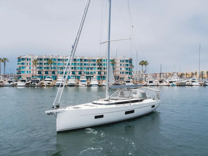 Kalesma Yacht Photos Pics 2021 Bavaria C50 Style yacht sailing in a marina with modern buildings in the background.