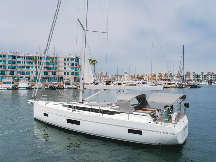 Kalesma Yacht Photos Pics 2021 Bavaria C50 Style yacht docked in a marina with modern buildings in the background.