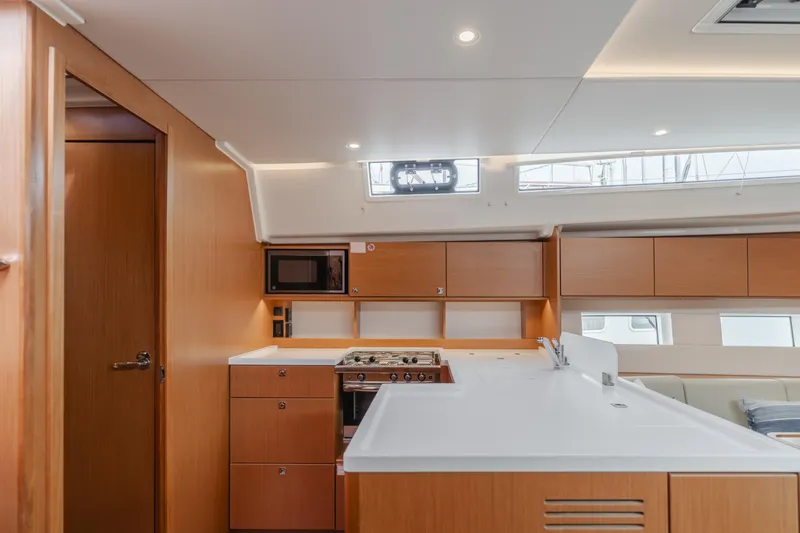 Kalesma Yacht Photos Pics Modern kitchen interior of 2021 Bavaria C50 Style yacht with wood cabinetry and white countertops.