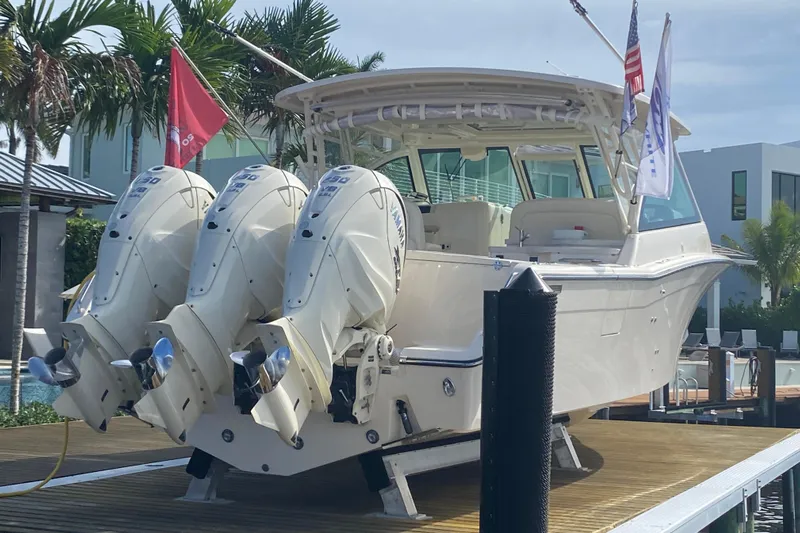  Yacht Photos Pics 2024 Grady-White Freedom 375 boat with triple outboard engines docked by palm trees.