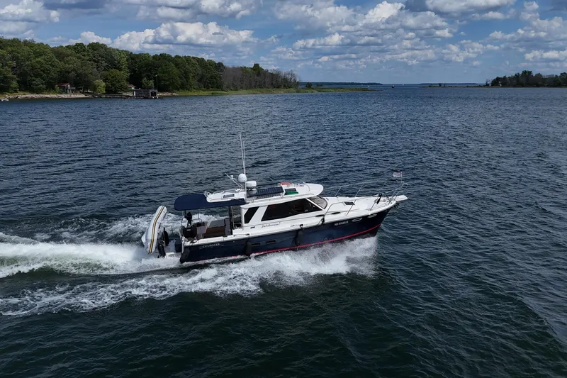 Yacht Photos Pics 2014 Cutwater C30 Sedan NW cruising on a scenic lake under a partly cloudy sky.