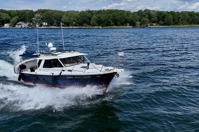  Yacht Photos Pics 2014 Cutwater C30 Sedan NW cruising on a scenic lake with lush shoreline.