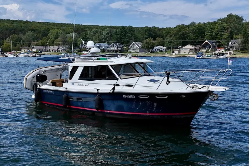  Yacht Photos Pics 2014 Cutwater C30 Sedan NW boat on a scenic lake with houses in the background.