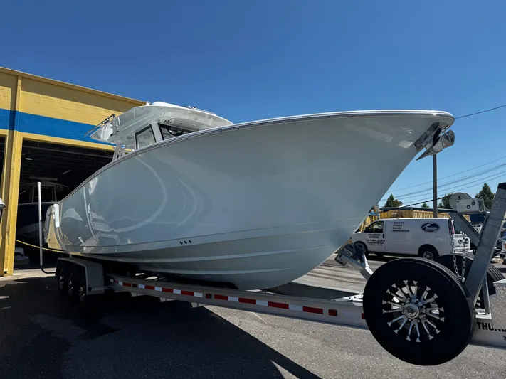  Yacht Photos Pics 2024 Sportsman Open 322 Center Console boat on trailer outside a garage.
