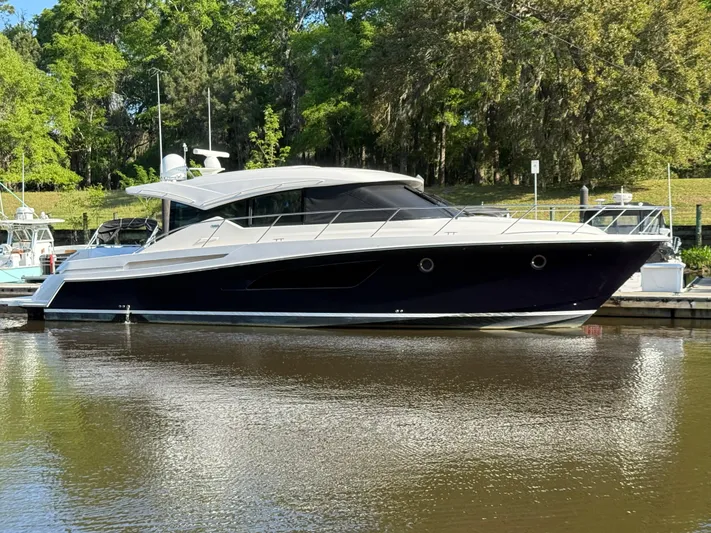 Swift Wing Yacht Photos Pics 2016 Tiara Yachts 50 Coupe docked on a calm river with lush greenery.
