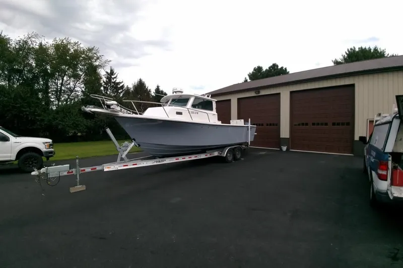  Yacht Photos Pics 2024 Parker 2820 XLD Sport Cabin boat on trailer outside large garage.