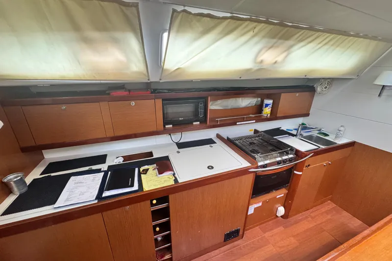  Yacht Photos Pics Interior of 2011 Beneteau Oceanis 50 yacht kitchen with stove, sink, and wooden cabinetry.