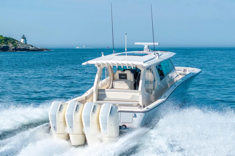 Dealership II Yacht Photos Pics 2023 Scout 530 LXF boat cruising near a lighthouse on a sunny day.