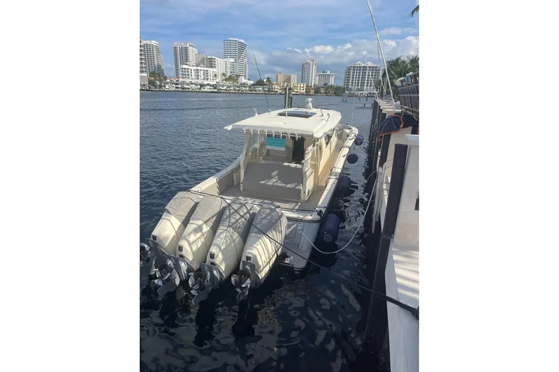 Dealership II Yacht Photos Pics 2023 Scout 530 LXF luxury boat docked in a marina with cityscape background.