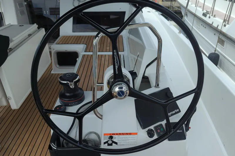 Her Intentions Yacht Photos Pics Steering wheel of 2021 Jeanneau Sun Odyssey 440 sailboat, featuring teak deck and navigation controls.