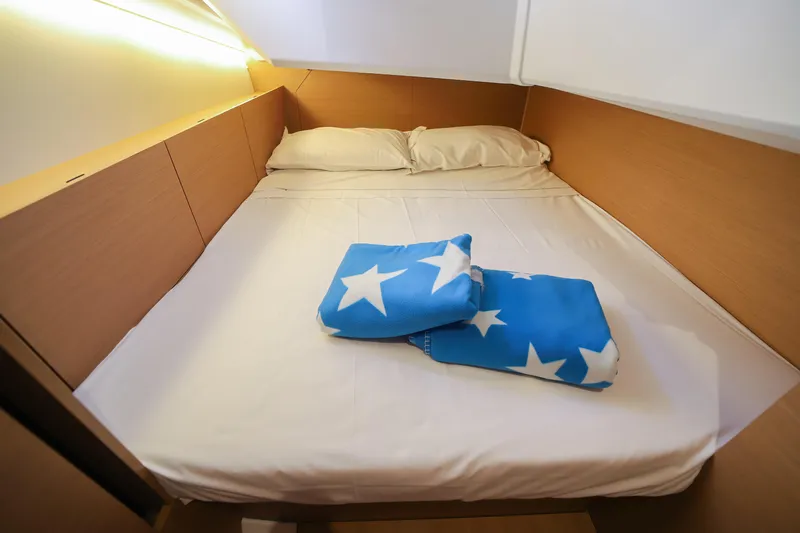 Twenty One Cent Yacht Photos Pics Cozy cabin bed in 2022 Jeanneau Sun Odyssey 380 yacht with star-patterned blanket.