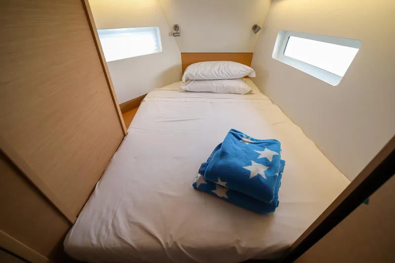Twenty One Cent Yacht Photos Pics Cozy cabin interior of 2022 Jeanneau Sun Odyssey 380 with bed and star-patterned blanket.