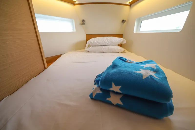 Twenty One Cent Yacht Photos Pics Cozy cabin interior of 2022 Jeanneau Sun Odyssey 380 with star-patterned blanket.