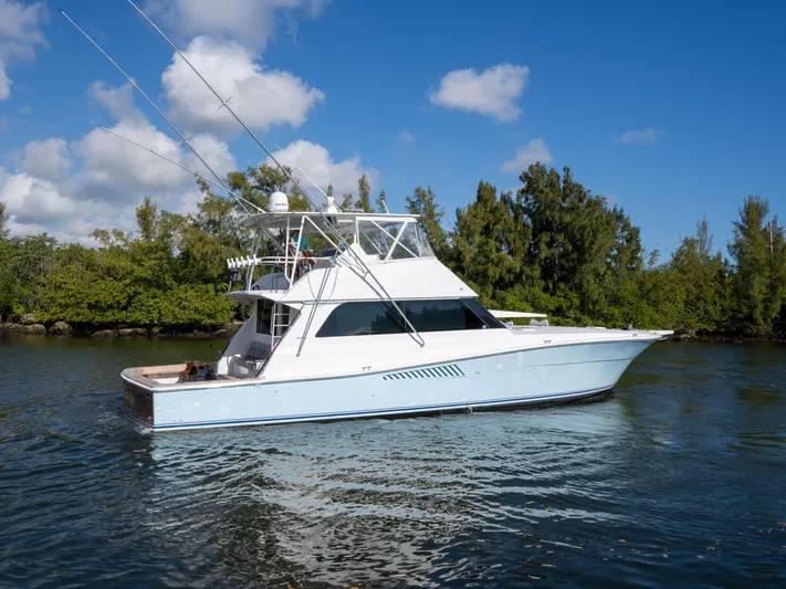 Samurai Yacht Photos Pics 1998 Viking 58 Convertible yacht on calm water, surrounded by lush greenery.