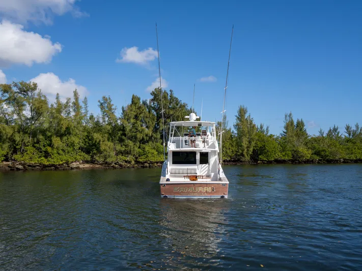 Samurai Yacht Photos Pics 1998 Viking 58 Convertible boat on calm water, surrounded by lush greenery.