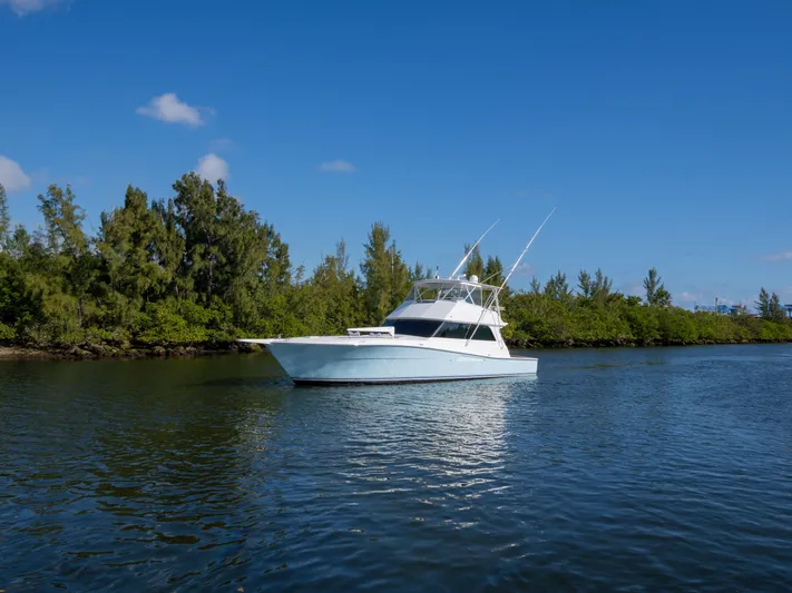 Samurai Yacht Photos Pics 1998 Viking 58 Convertible yacht on a serene waterway, surrounded by lush greenery.
