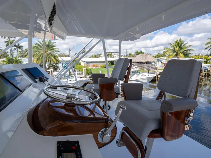 Samurai Yacht Photos Pics Helm of 1998 Viking 58 Convertible yacht with steering wheel and chairs, docked near palm trees.
