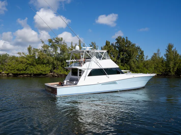 Samurai Yacht Photos Pics 1998 Viking 58 Convertible yacht on calm water, surrounded by lush greenery.