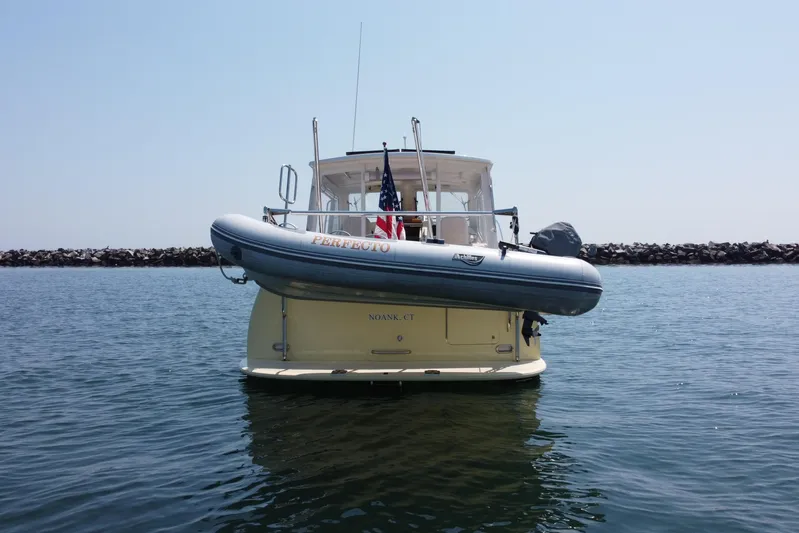 Tango Yacht Photos Pics 2006 MJM 34z Downeast boat with dinghy, anchored in calm waters, rear view.