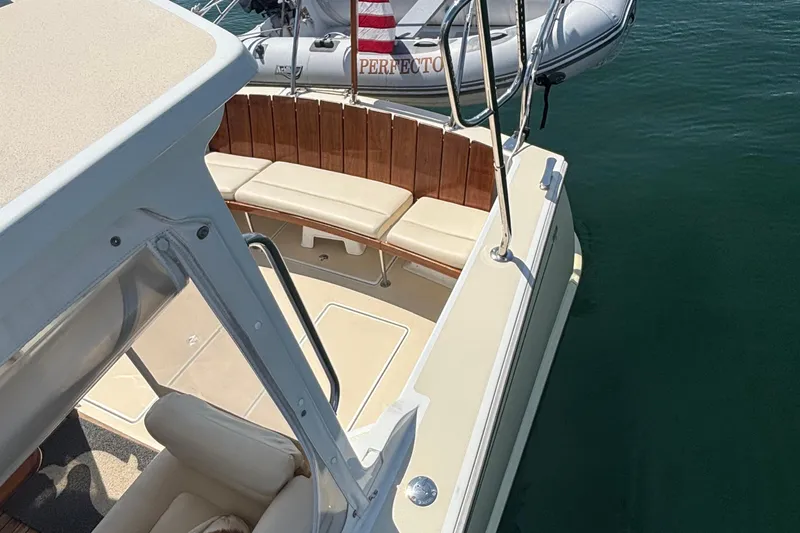 Tango Yacht Photos Pics 2006 MJM 34z Downeast boat with cushioned seating and dinghy in water.