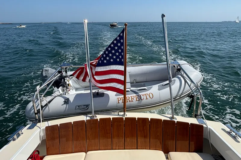 Tango Yacht Photos Pics 2006 MJM 34z Downeast boat towing dinghy with American flag on open water.