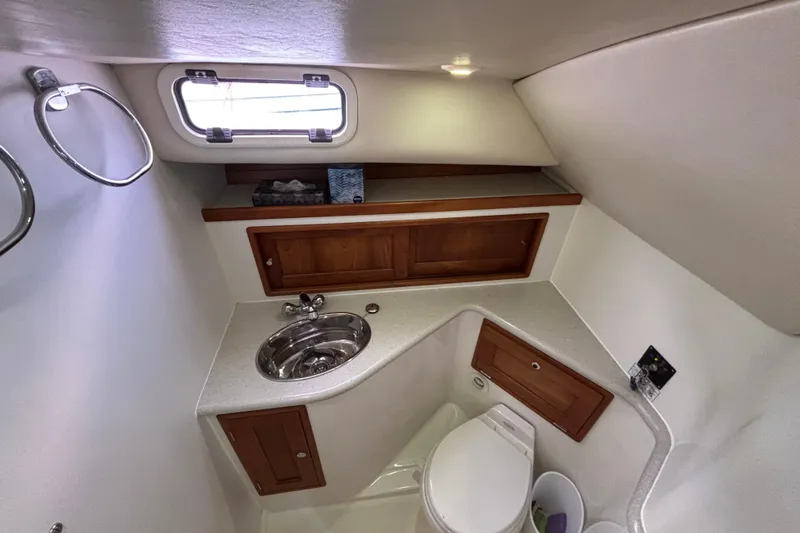 Tango Yacht Photos Pics 2006 MJM 34z Downeast boat bathroom with sink, toilet, and wooden cabinets.