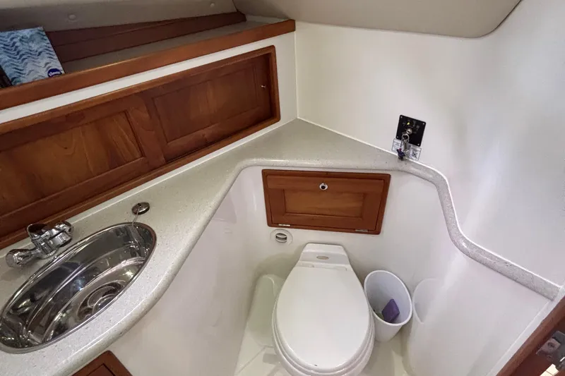 Tango Yacht Photos Pics 2006 MJM 34z Downeast boat bathroom with sink, toilet, and wooden cabinetry.
