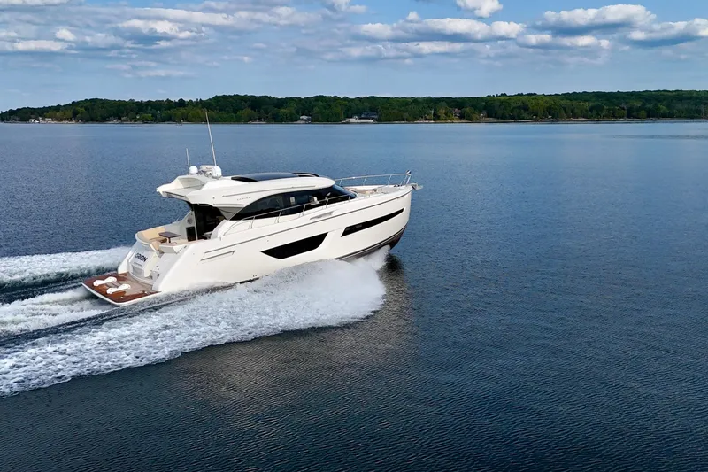Orion Yacht Photos Pics 2018 Carver C52 Coupe yacht cruising on a serene lake under a partly cloudy sky.