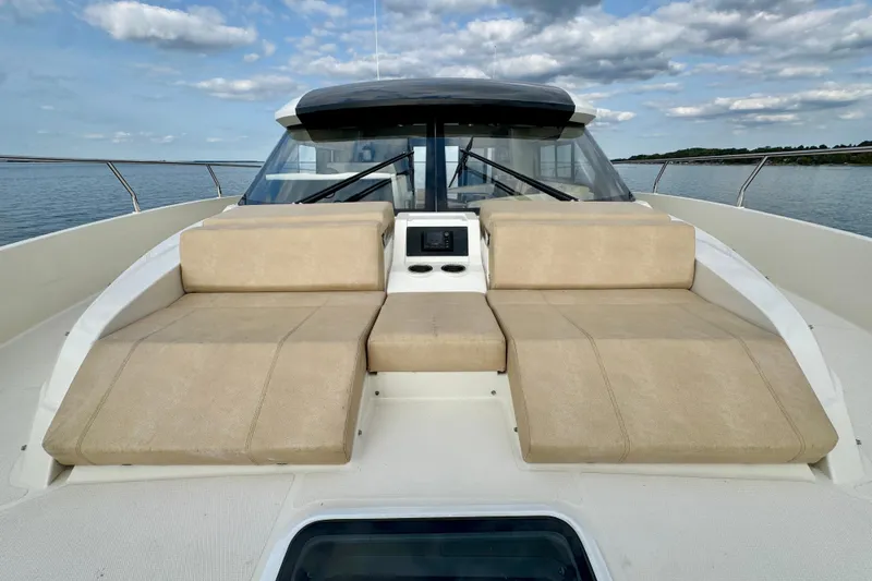 Orion Yacht Photos Pics 2018 Carver C52 Coupe yacht with beige sun loungers on deck, under a partly cloudy sky.