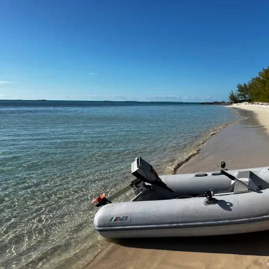 Monlove Yacht Photos Pics Inflatable boat on a serene beach with clear blue water and a sunny sky.