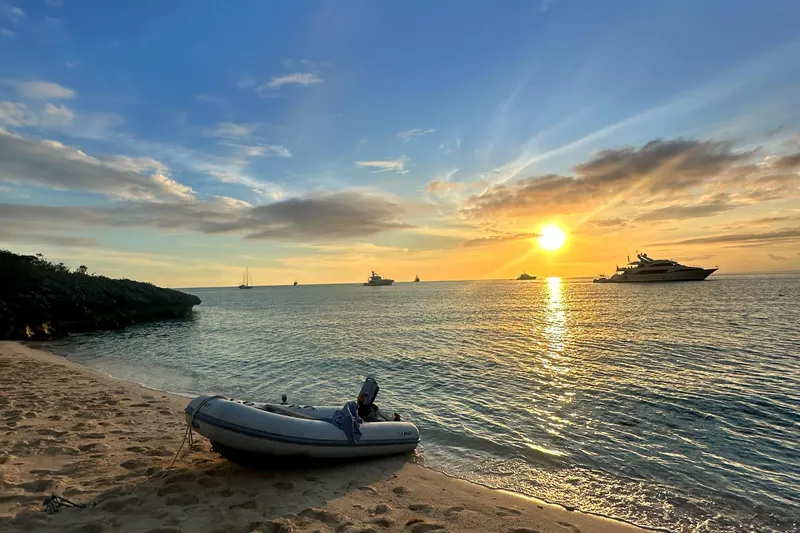 Monlove Yacht Photos Pics Sunset over ocean with boats, including a 2007 Beneteau Oceanis Clipper 393, near sandy beach.