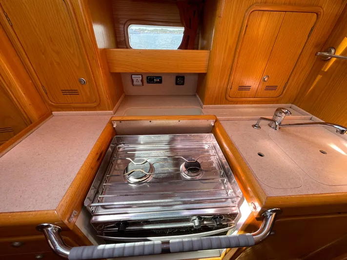 Chandelle Yacht Photos Pics 2008 Alubat OVNI 435 yacht kitchen with stove, sink, and wooden cabinetry.
