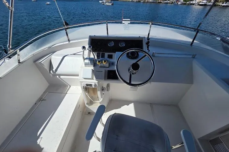  Yacht Photos Pics 1993 McKinna 48 Pilothouse helm with steering wheel and controls, overlooking serene waters.