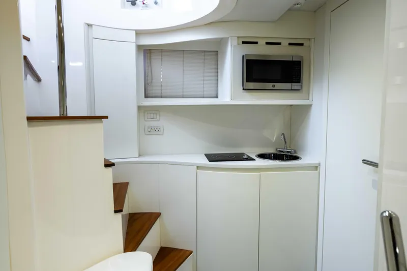 One Spin 2 Yacht Photos Pics Compact kitchen area in a 2017 Pershing 74 yacht with modern appliances and sleek design.