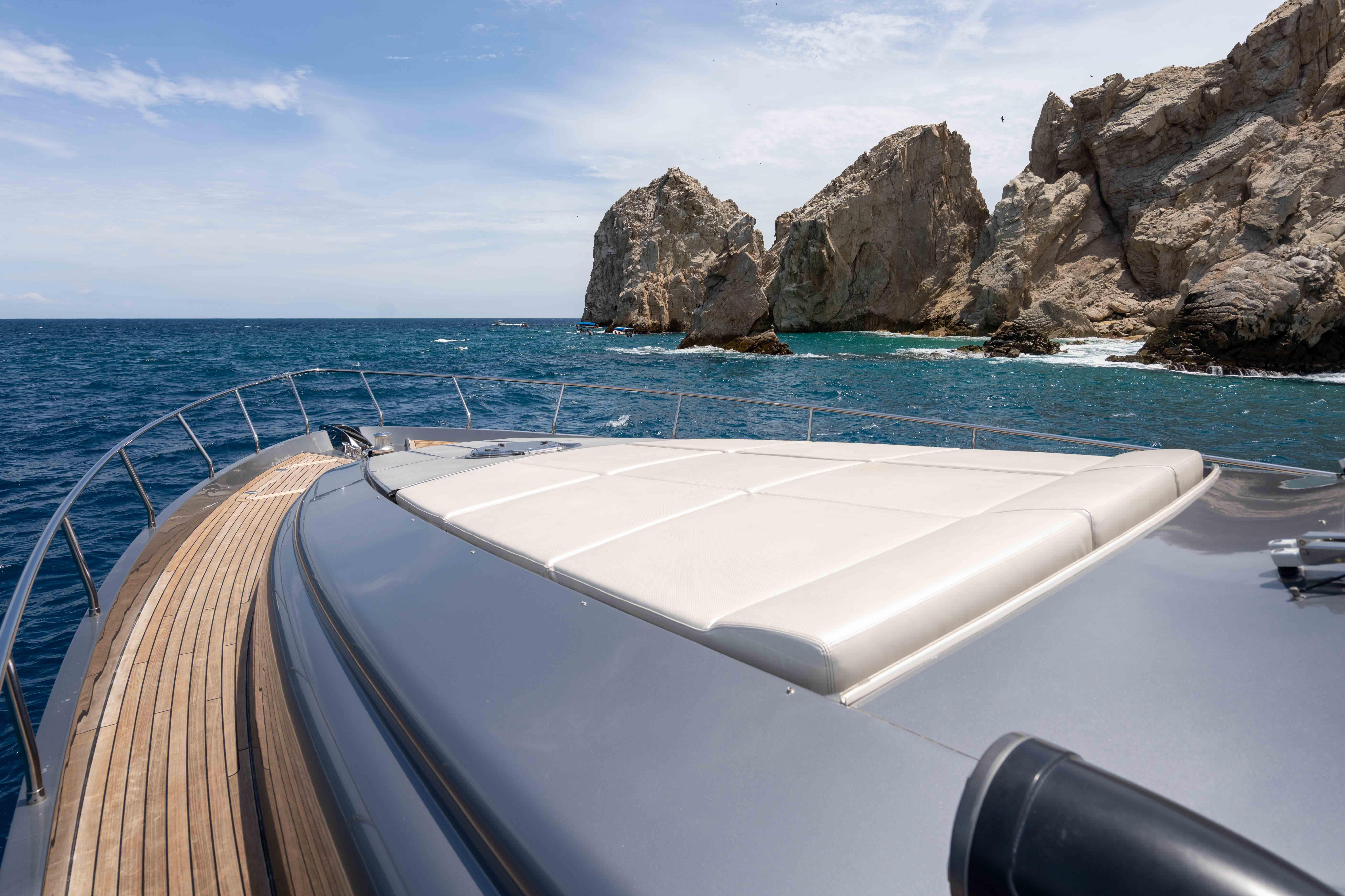 2017 Pershing 74 yacht cruising near rocky coastline under clear skies.