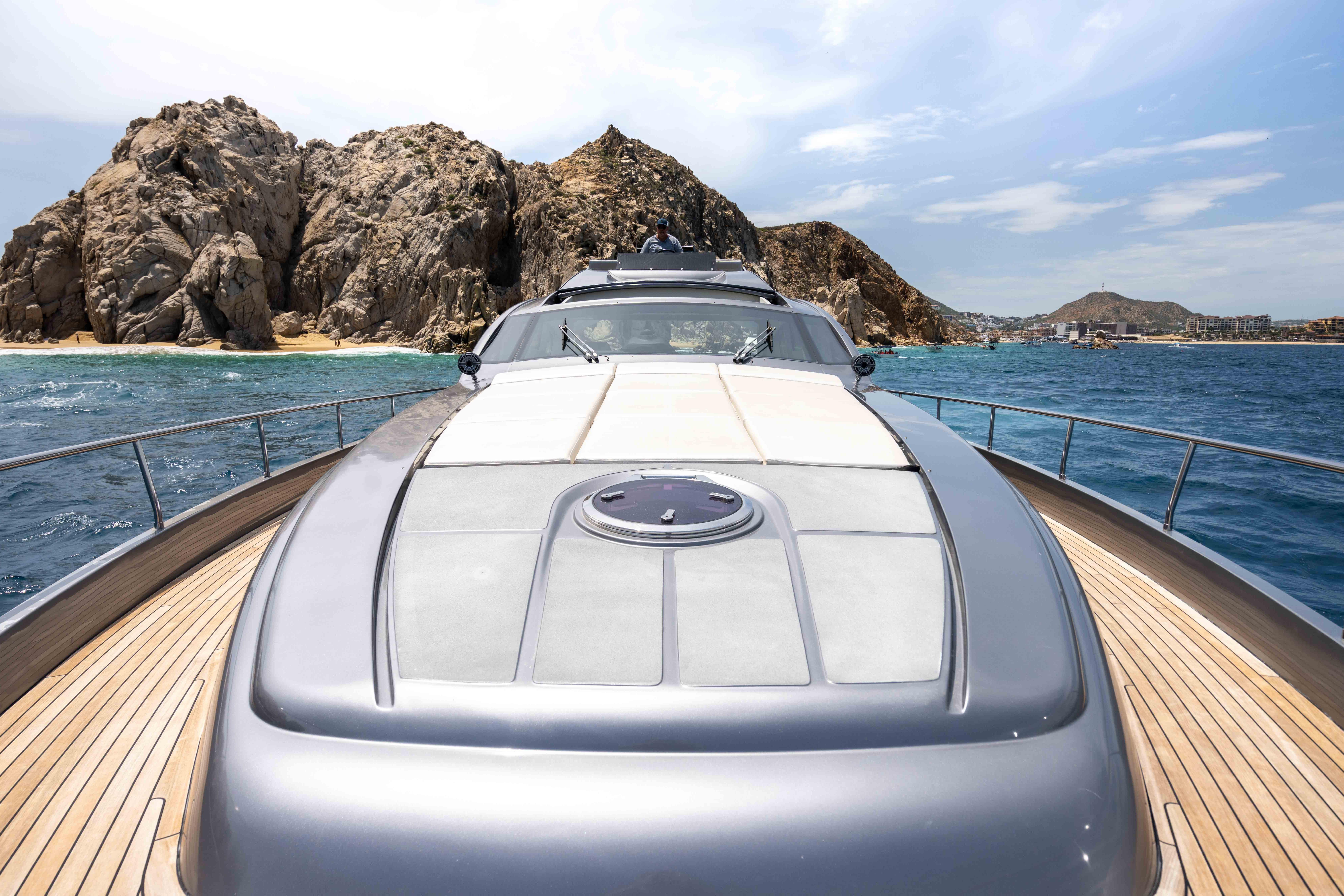 2017 Pershing 74 yacht cruising near rocky coastline under clear skies.