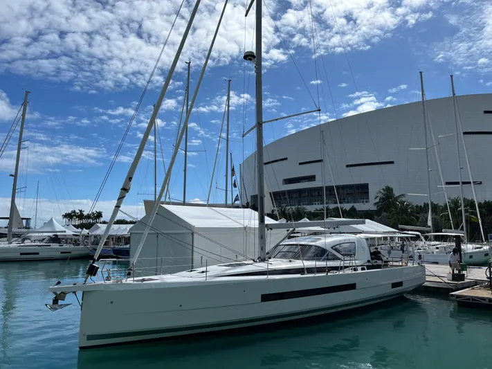  Yacht Photos Pics 2024 Jeanneau 55 sailboat docked at marina, clear sky, modern architecture in background.