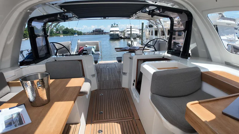  Yacht Photos Pics Luxurious 2024 Jeanneau 55 yacht interior with elegant seating and wooden accents at a marina.