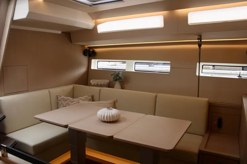  Yacht Photos Pics Modern interior of 2024 Jeanneau 55 yacht with beige seating and dining table.