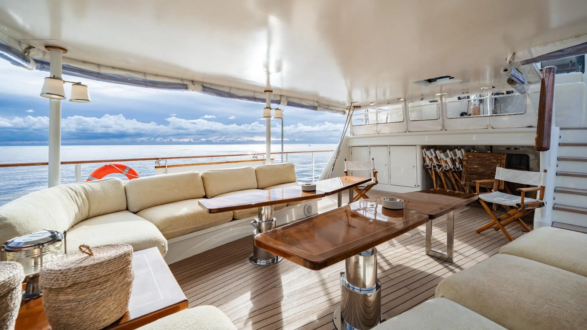 Luxurious yacht deck with comfortable seating, wooden tables, and ocean view, custom model from 1990.