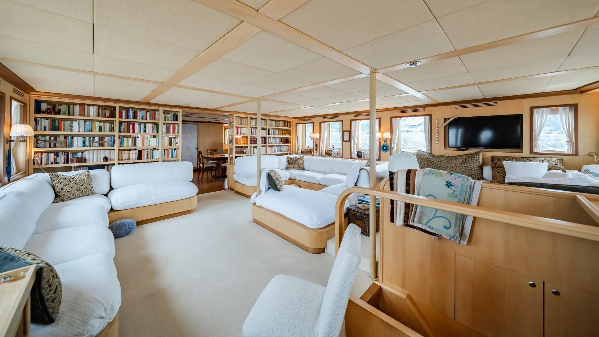 Luxurious yacht interior with white sofas, bookshelves, and a flat-screen TV, custom 1990 model.