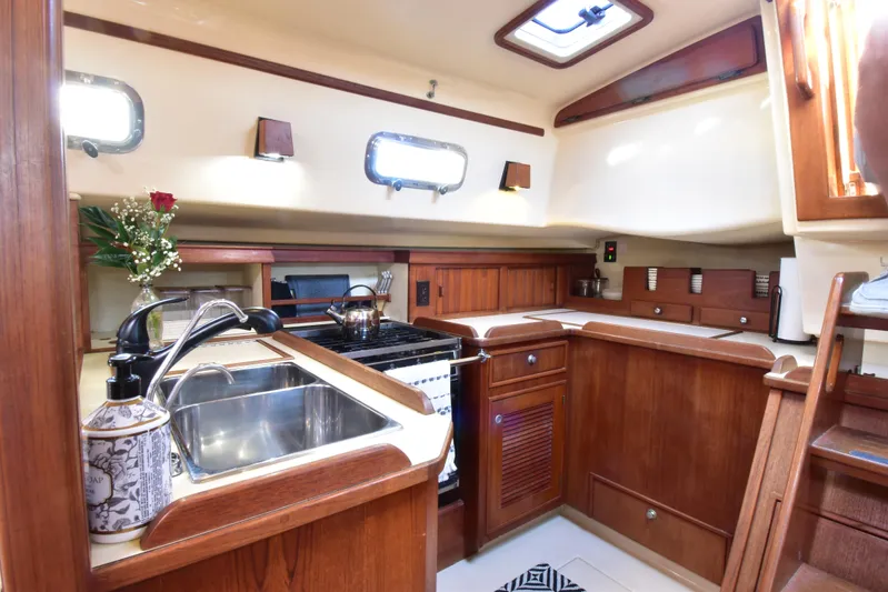 Aftia Yacht Photos Pics Island Packet 380 yacht kitchen interior, 1999 model, featuring wooden cabinetry and stainless steel sink.